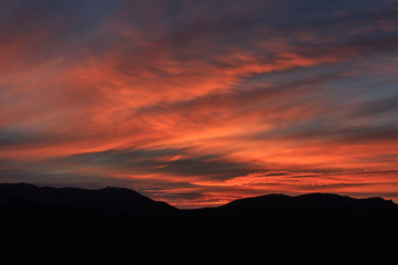 Reddish sunrise with clouds and mountains. Atmospheric effects concept