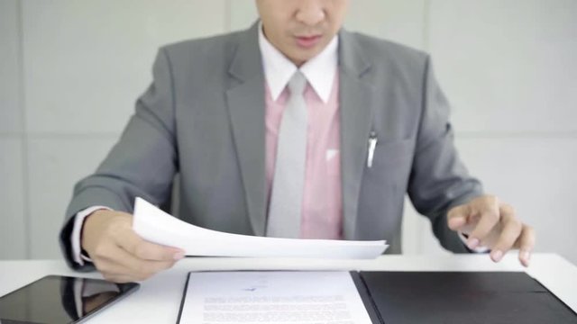 Slow motion - Asian business man working at office with tablet and documents on his desk, consultant lawyer concept.
