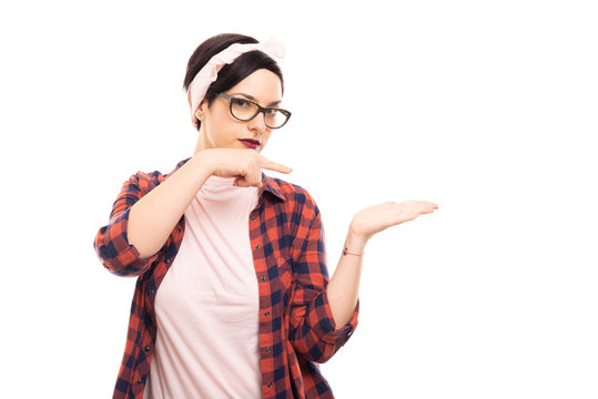 Young pretty pin-up girl wearing glasses pointing copyspace.