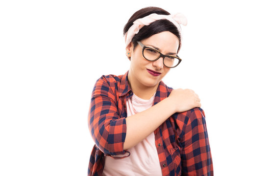 Young pretty pin-up girl wearing glasses showing shoulder pain gesture.