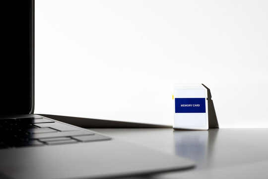 Memory card with empty surface next to a notebook computer. Concept SD card product photo.