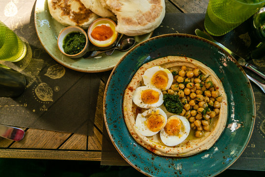 Middle eastern stile breakfast - hummus with eggs, pitas and dips