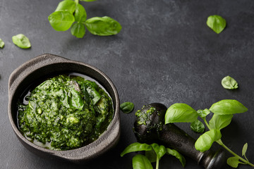 Basil pesto sauce with parmesan cheese, nuts, olive oil and garlic in black cast iron mortar, close up view