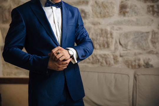 A close-up of a cropped frame of a man in an expensive classic costume looks at his watch. The businessman is in a hurry and looks at the time. A handsome man with a precious watch and a gold ring.