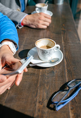 Closeup of hands of business woman and man with mobile having coffee