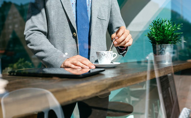 Unrecognizable businessman stirring coffee in a coffee shop