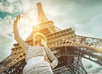 Woman tourist selfie near the Eiffel Tower in Paris under sunlight