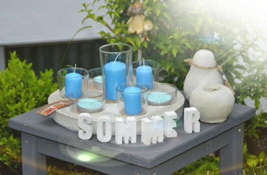 Sommerarrangement aus Beton mit blauen Kerzen