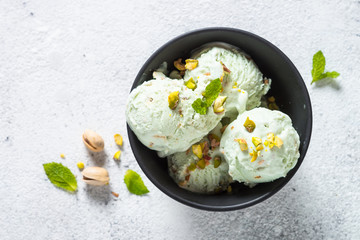 Pistachios ice cream in bowl on white stone table.