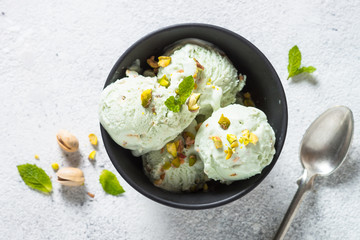 Pistachios ice cream in bowl on white stone table.