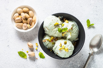 Pistachios ice cream in bowl on white stone table.