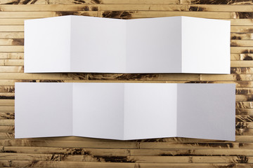 Mockup of opened four fold brochure at bamboo background.