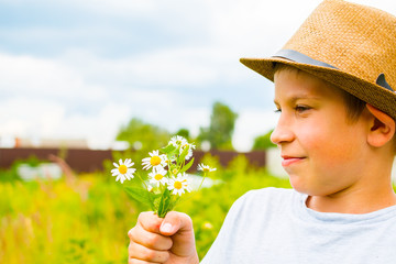 boy 10 years with daisies in his hands