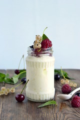 Homemade yoghurt with different berries and mint in a jar, vertical
