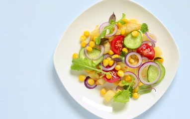 Salad with corn, fresh vegetables and baked potatoes, top view, copy space