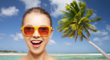 travel, tourism, summer holidays, vacation and people concept - smiling young woman or teenage girl in sunglasses over exotic tropical beach background