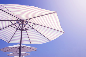 striped beach umbrellas on blue sky background in sunlight