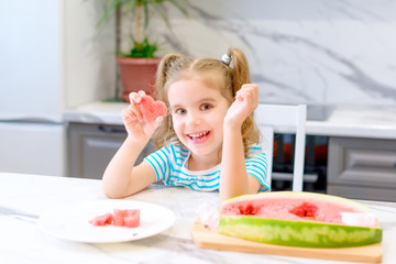 child eats watermelon. happy baby girl eating watermelon in summer in the kitchen. selective focus.
