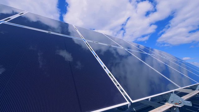 Cloudy blue sky is mirroring in the solar array