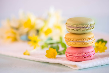 Fototapeta na wymiar Colorful macarons on towel with yellow flowers and narcissus