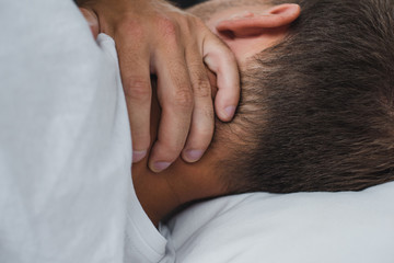 close-up view of man suffering from pain in neck while lying on bed