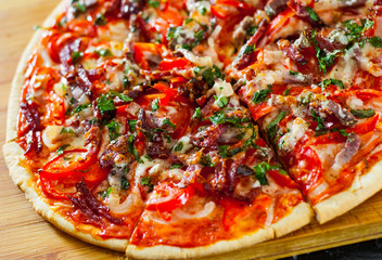 sliced Pizza with Mozzarella cheese, Ham, Tomatoes, salami, pepper, bacon, pepperoni, Spices and Fresh Basil. Italian pizza