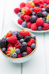 Fresh berry salad on blue dishes. Vintage wooden background.