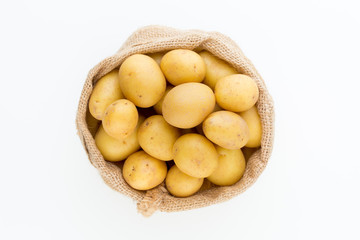 Sack of fresh raw potatoes on wooden background, top view