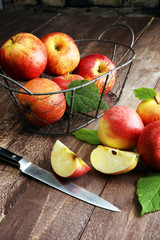 Ripe red apples with leaves on wooden background