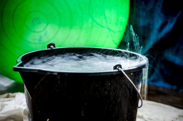 Rainy weather on the terrace in summer. The rain falls into the bucket and creates splashes.