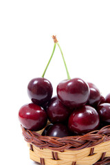 Yellow wooden basket with red sweet cherry isolated on a white background..