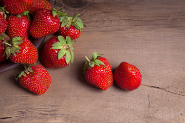Strawberry fresh ripe sweet berry in clay plate on wooden background.