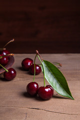 Clay plate with red sweet cherry on wooden background.