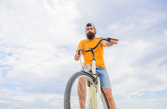 Man bearded hipster rides bicycle bottom view sky background. Overcome obstacles on bike. Hipster ready to perform trick. Modern bicycle riding culture. Optimise cycling performance