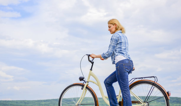 Woman rides bicycle sky background. How to learn to ride bike as an adult. Active leisure. Girl ride bicycle. Healthiest most environmentally friendly and most satisfying forms of self transportation