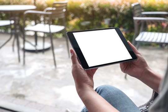 Mockup image of woman's hands holding black tablet pc with white blank desktop screen in cafe