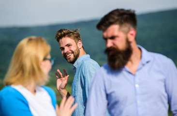 Jealous concept. Man with beard jealous aggressive because girlfriend interested in handsome passerby. Passerby smiling to lady. Husband strictly watching his wife looking at another guy while walk