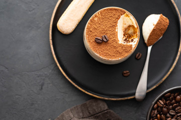 Delicious Italian dessert tiramisu, chocolate, cocoa and coffee beans on a black background. Top view with copy space.