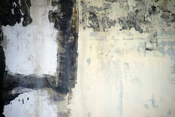 Schwarze Farbstriche an der Wand / Die Nahaufnahme einer hellen Mauer mit schwarzen Farbstrichen und Farbflecken.