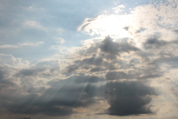 Fototapeta na wymiar Promienie słońca prześwitujące przez chmury na tle błękitnego nieba