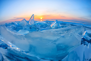 Transparent blue Toros Baikal ice is shining through the crack sunset