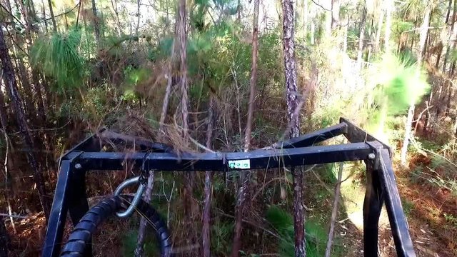 point of view on top of a bush hog going through brush and clearing trees and mulching