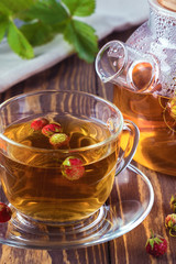 Fruit tea with wild berries in glass cup, on wooden background.Healthy drink with forest strawberry.Vertical image.