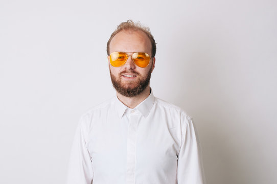 Portrait of young bearded man wearing yellow sunglasses and looking confident at the camera