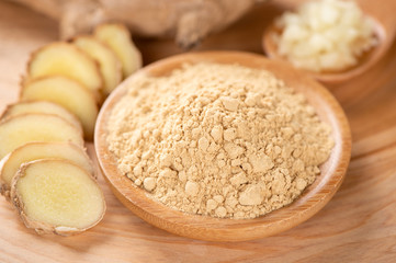 Ginger root, ginger slice and ginger powder on wooden background table, space for text.