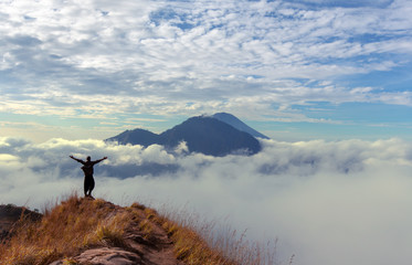  Hiker  rising hands on walk way at volcano Batur, Bali island, Indonesia