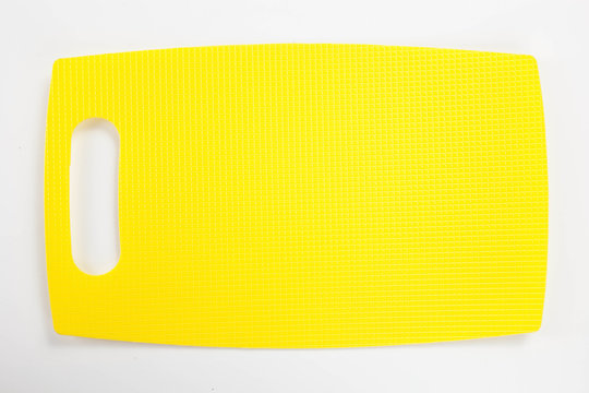 Yellow plastic kitchen cutting board isolated on white background