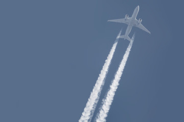 passenger plane fly with a contrail flying on the dark blue sky background