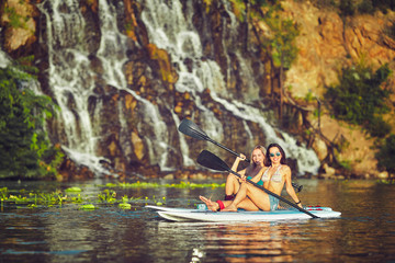 SUP Stand up Surf girl with paddle at sunset