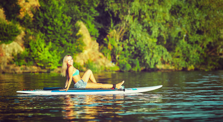 SUP Stand up Surf girl with paddle at sunset